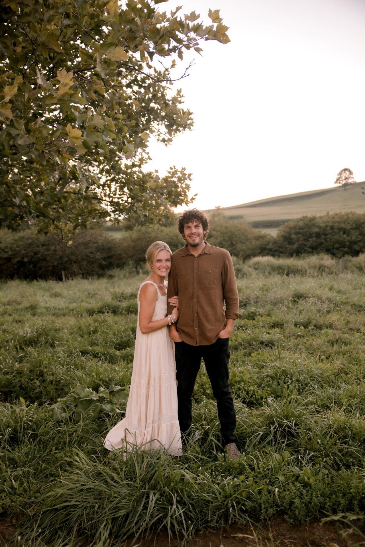 Sarah and her husband in a field full of greenery.